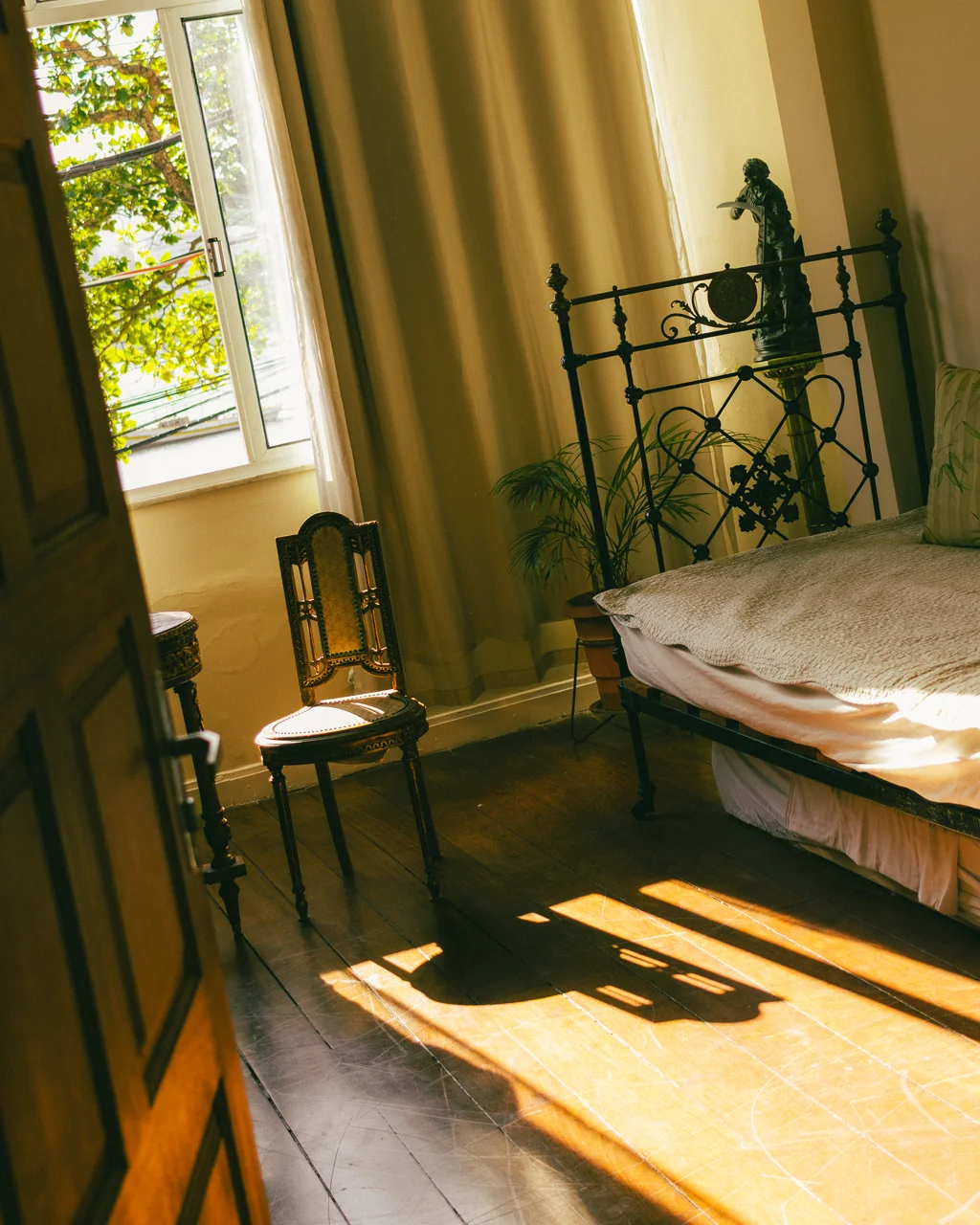 Quarto com cama de ferro e luz lateral dourada da manhã, Hotelinho da Urca