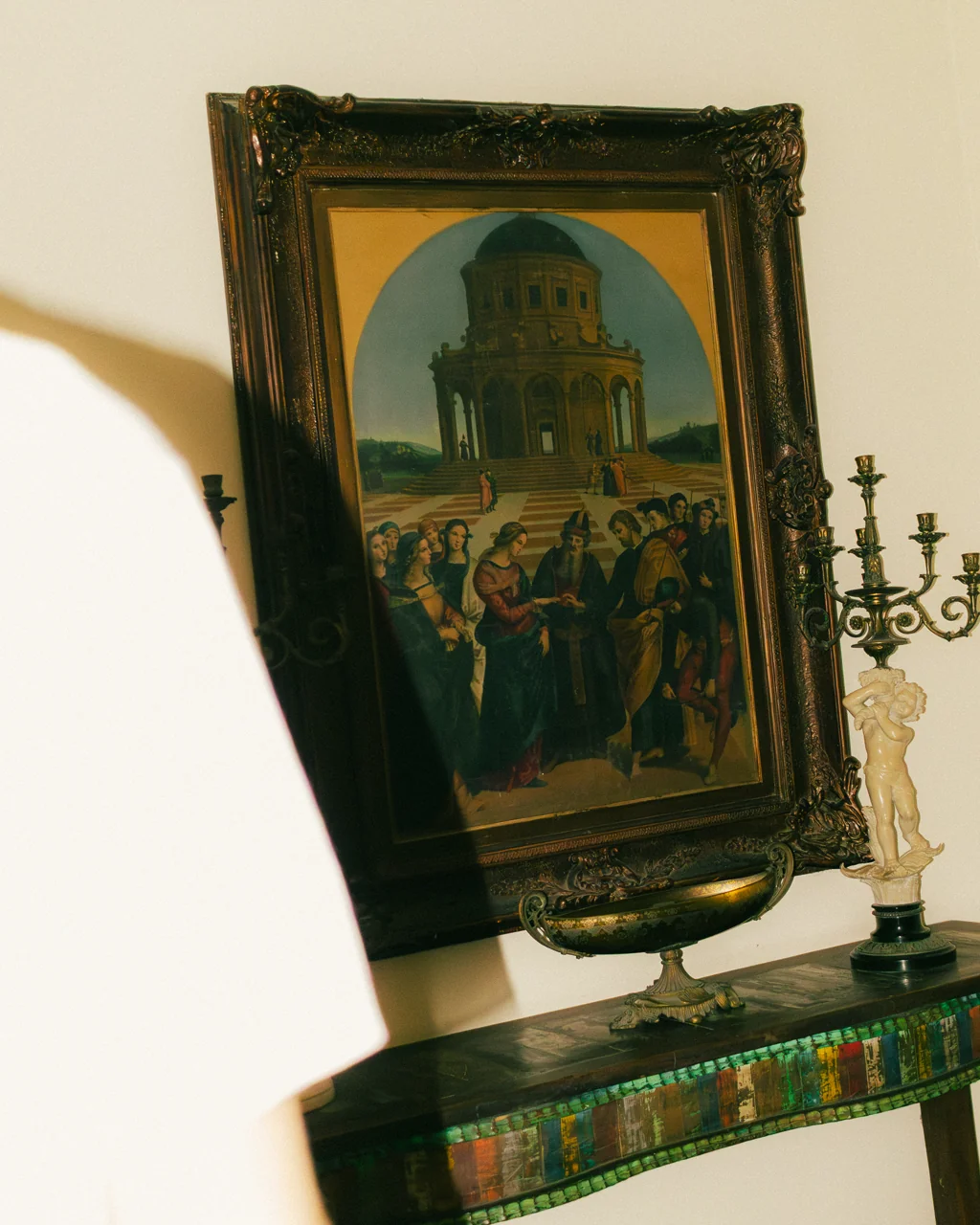 Detalhe de pintura clássica emoldurada, castiçal e console no Hotelinho da Urca
