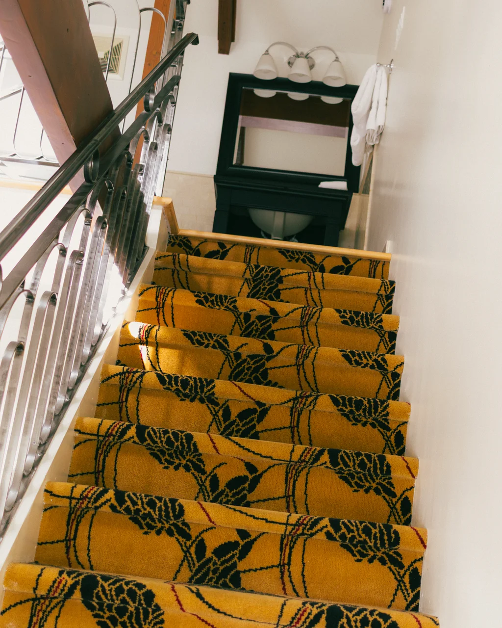 Escada com tapete floral amarelo e console preto no Manoir d'Auteuil, Quebec City