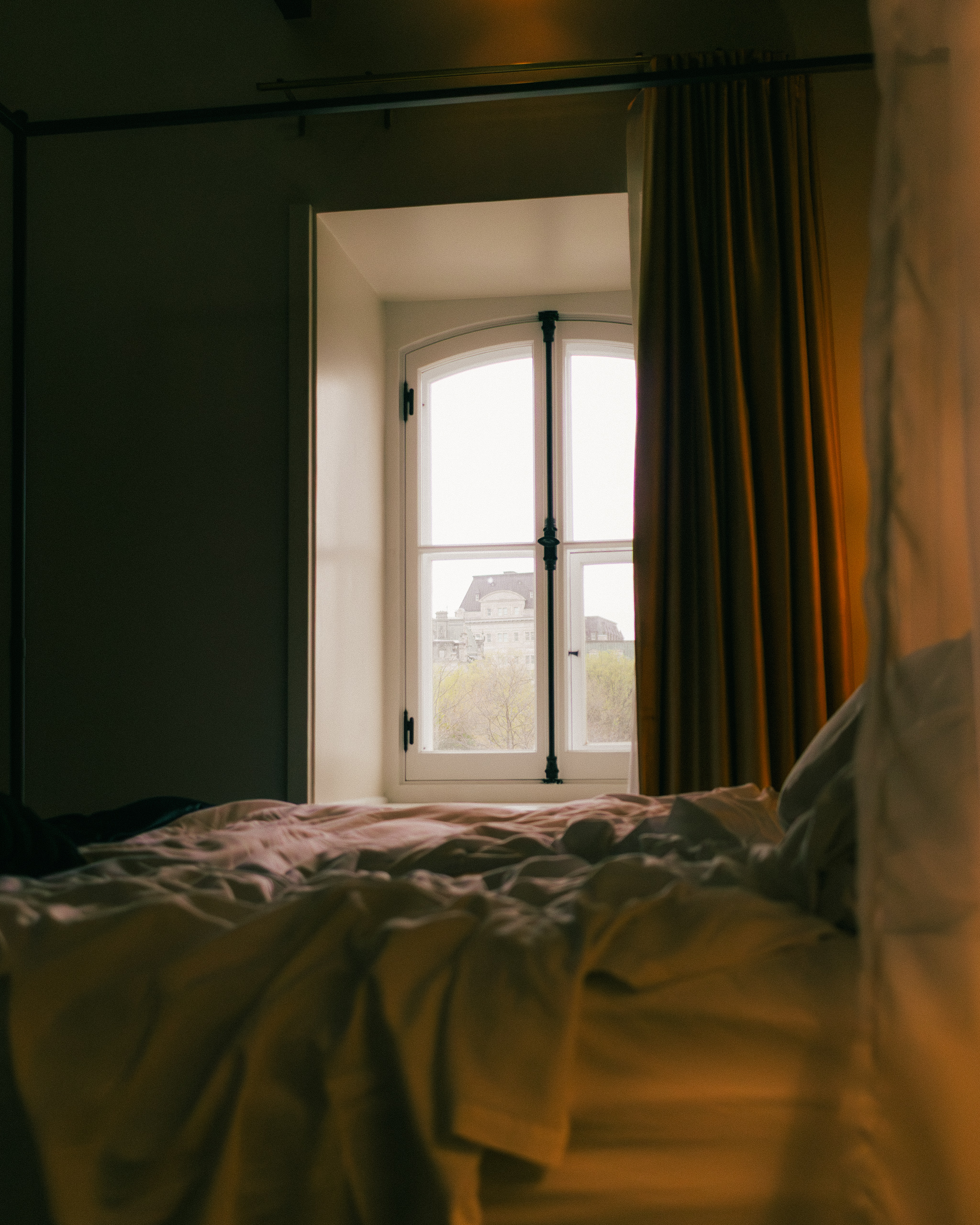 Quarto com janela em arco e vista da cidade ao amanhecer no Manoir d'Auteuil, Quebec City