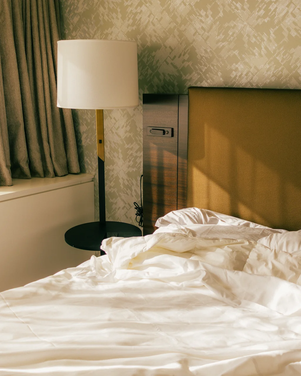 Cama com luz dourada, abajur e papel de parede verde no Le Centre Sheraton, Montréal